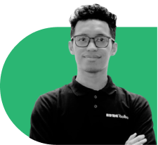 Portrait of a man with glasses wearing a black polo, arms crossed, against a green rounded background.